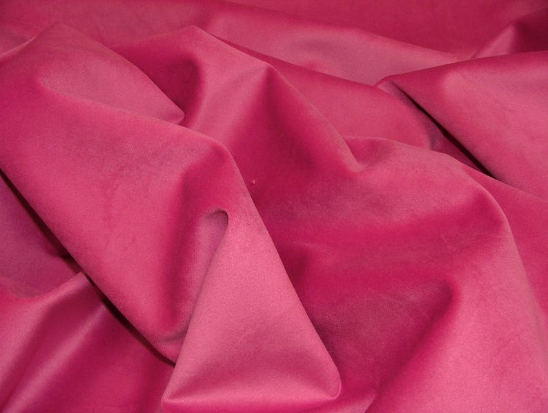 May include: A close-up of a soft, pink fabric with a smooth texture. The fabric is folded and draped, creating a luxurious and elegant look.