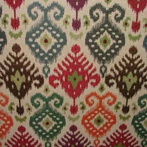 May include: A colourful fabric with a repeating pattern of brown, green, red, orange, and white. The pattern is a traditional ikat design.