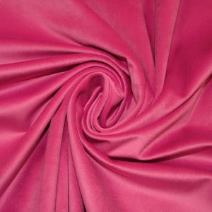May include: A close-up of a soft, pink fabric with a smooth, velvety texture. The fabric is draped and folded, creating a luxurious and elegant look.