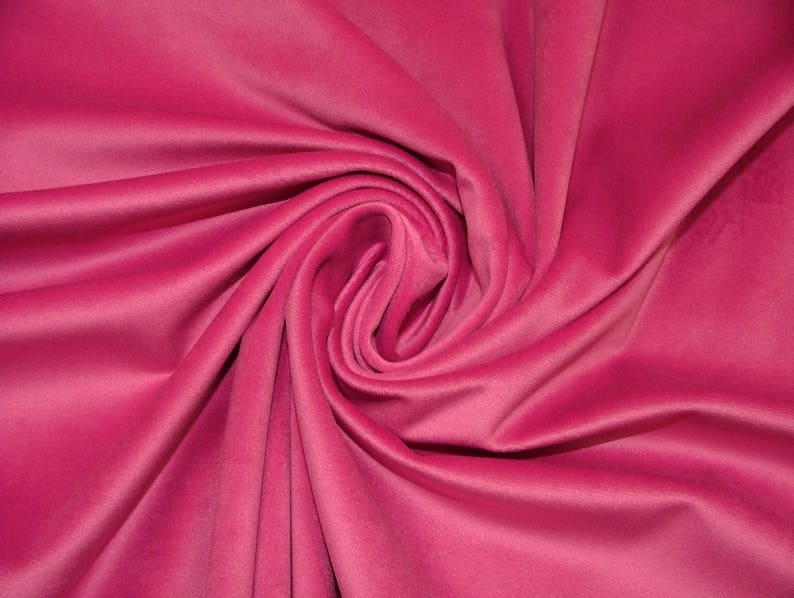 May include: A close-up of a soft, pink fabric with a smooth, velvety texture. The fabric is draped and folded, creating a luxurious and elegant look.