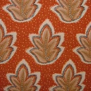 Könnte beinhalten: Nahaufnahme eines Stoffes mit einem sich wiederholenden Muster aus stilisierten Blättern in Braun-, Beige- und Blautönen auf einem orangebraunen Hintergrund.