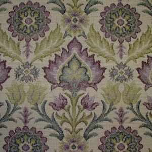 May include: A beige fabric with a repeating pattern of purple, green, and brown floral designs. The fabric has a textured surface.
