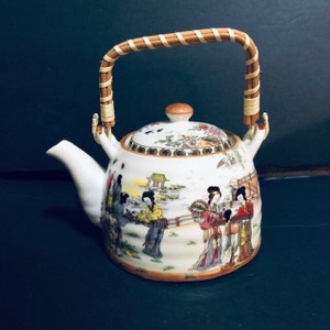 May include: White porcelain teapot with a bamboo handle and a painted scene of Japanese women in a garden. The teapot has a lid with a floral design.