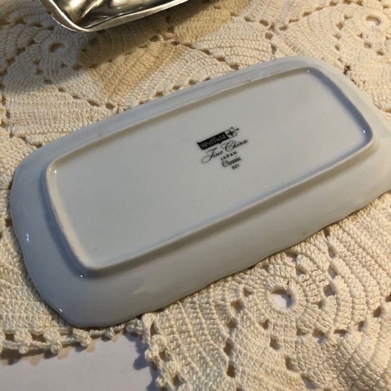 May include: White rectangular butter dish with a raised edge. The bottom of the dish has the text "Sheffield Fine China Japan Classic 501" printed on it.