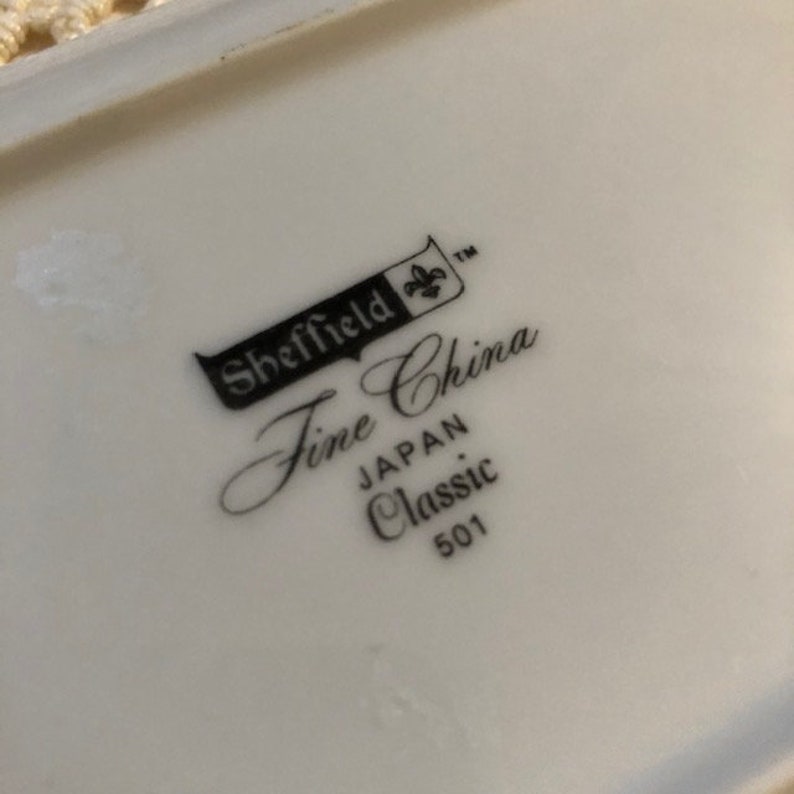 May include: Close-up of a white ceramic plate with black text that reads "Sheffield Fine China, Japan Classic 501".