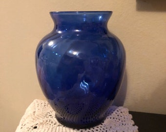 May include: A cobalt blue glass vase with a rounded body and a wide mouth.