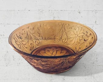 May include: A vintage amber glass bowl with a floral design. The bowl is slightly flared and has a scalloped edge.