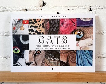 Puede incluir: Un calendario de 2026 con un collage de caras y patrones de pelaje de gatos. La palabra "CATS" se muestra de forma destacada, con el texto "FROM HISTORY, MYTH, FOLKLORE & POP CULTURE, BUT MADE REAL(ISH)". El calendario está sobre una estantería de madera contra una pared de ladrillos blancos.