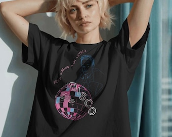 Puede incluir: Camiseta negra con un diseño de bola de discoteca, la palabra "DISCO" y la frase "Been kissing a lot lately." El diseño incluye elementos rosas, azules y blancos. Una prenda de vestir informal.