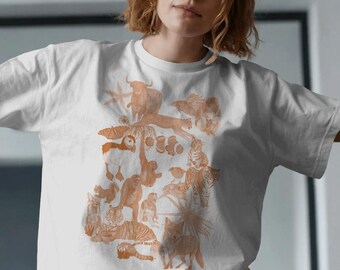 Puede incluir: Camiseta blanca con una ilustración naranja de varios animales, incluyendo tigres, monos y un lobo. El diseño detallado presenta una variedad de vida silvestre. La camiseta tiene cuello redondo y mangas cortas.