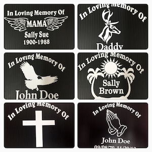 May include: Six black memorial plaques with white text and images. The plaques read "In Loving Memory Of" with a name and dates. The images include a pair of wings, a deer, a palm tree, an eagle, a cross, and praying hands.