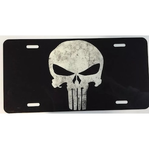 May include: Black license plate with a white skull and crossbones graphic. The skull has a distressed, weathered look.