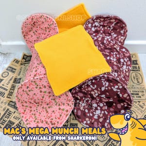 May include: A set of four fabric food-shaped dog toys. The toys are shaped like a hamburger, a slice of cheese, and two slices of pepperoni. The toys are made of soft, durable fabric and are perfect for interactive play. The toys are pink, yellow, and brown with a speckled pattern.