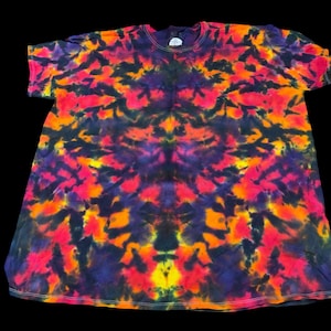 May include: A short-sleeved tie-dye t-shirt in a vibrant pattern of red, orange, yellow, and purple hues. The shirt has a crew neck and a relaxed fit. The tie-dye design creates a symmetrical, abstract pattern across the fabric.