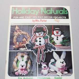 May include: A magazine cover titled "Holiday Naturals" featuring holiday decor projects. The cover showcases various handmade decorations, including snowmen, wreaths, and bunnies. The projects are made from natural materials like raffia and straw. The text reads "Fun and Easy Holiday-Decor Projects by Mrs. Putter."