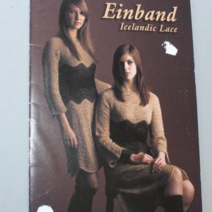May include: A book cover featuring two women modeling knitted dresses. The dresses are beige with a black lace design at the waist. The text "Einband Icelandic Lace" is displayed in a gold color on a brown background.