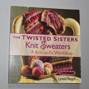 May include: A book titled "The Twisted Sisters Knit Sweaters: A Knit-to-Fit Workshop" features a colorful knitted sweater draped over a chair. The cover also displays several balls of yarn in a wooden bowl, with the author's name at the bottom.