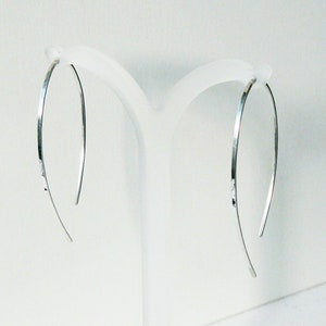 May include: A pair of silver hoop earrings with a hammered finish. The earrings are thin and delicate, and they hang from a simple hook.