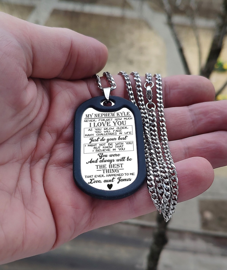May include: A black dog tag necklace with a silver chain. The dog tag has a message for a nephew, "My Nephew Kyle Never forget how much I love you..."