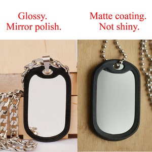 May include: Two dog tags on silver chains. The tag on the left has a mirror polish finish. The tag on the right has a matte coating. Both tags are black with a silver rim.