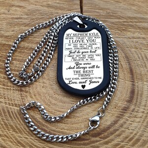 May include: A black dog tag necklace with a silver chain. The dog tag has a message engraved on it that reads "My Nephew Kyle Never forget how much I love you As you grow older you will face many challenges in life Just do your best Might not be with you But know that I believe in you You were And always will be The best -thing- That ever happened to me Love, aunt James"