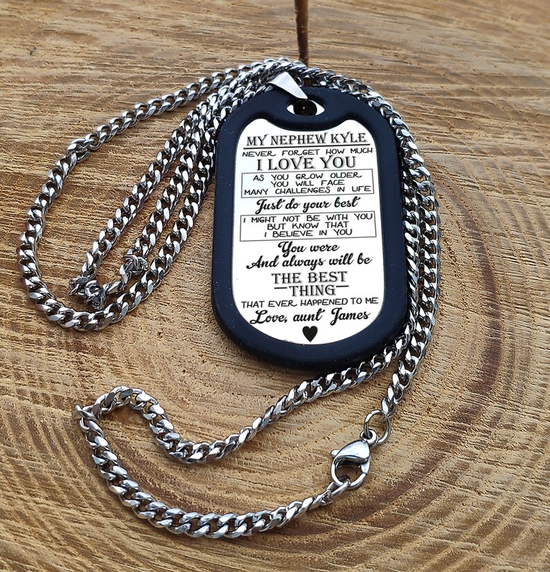 May include: A black dog tag necklace with a silver chain. The dog tag has a message engraved on it that reads "My Nephew Kyle Never forget how much I love you As you grow older you will face many challenges in life Just do your best Might not be with you But know that I believe in you You were And always will be The best -thing- That ever happened to me Love, aunt James"