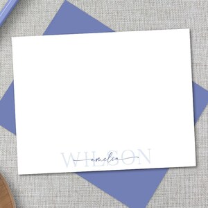 K&ouml;nnte beinhalten: Eine wei&szlig;e Karte mit einem blauen Umschlag. Die Karte tr&auml;gt den Text "WILSON" in Blau mit dem Namen "amelia" darunter, der in Kursivschrift geschrieben ist.