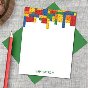 May include: A white card with a green envelope. The card has a border of colorful toy building blocks at the top and the name "SAM WILSON" printed at the bottom.