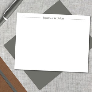 May include: A white stationery card with a gray envelope. The card has a line at the top and bottom and the text "Jonathan W. Baker" printed in the center.