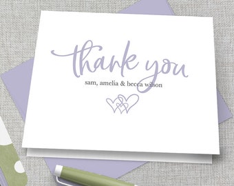 May include: A white thank you card with a purple script font that says "thank you" and the names "sam, amelia & becca wilson" in a smaller font. The card has a purple heart design.