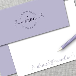 May include: A white envelope with a purple envelope on top. The purple envelope has a return address stamp with the text "1234 N. Main Street, wilson, Chicago, IL 60601". The white envelope has the text "daniel & amelia" with a heart symbol.