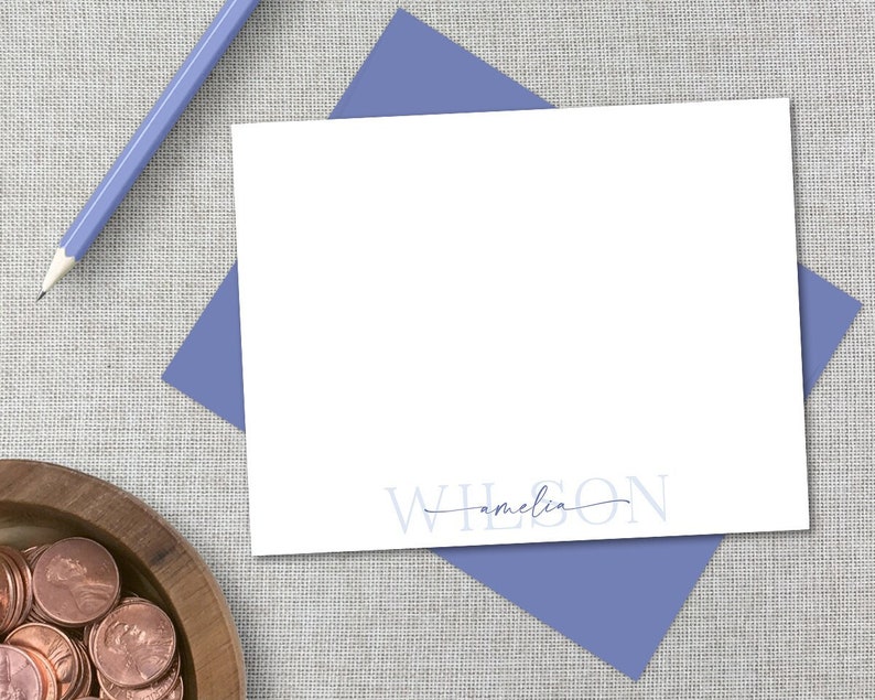 K&ouml;nnte beinhalten: Eine wei&szlig;e Karte mit einem blauen Umschlag. Die Karte tr&auml;gt den Text "WILSON" in Blau mit dem Namen "amelia" darunter, der in Kursivschrift geschrieben ist.