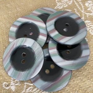 May include: Six black and white striped buttons with a black center and two holes. The buttons have a subtle shimmer and a green and pink color variation in the stripes.