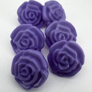May include: Six purple rose-shaped embellishments. These decorative elements have a glossy finish and detailed petal design. Ideal for crafting or adding a floral touch to projects. The roses are approximately 2.5 cm in diameter.
