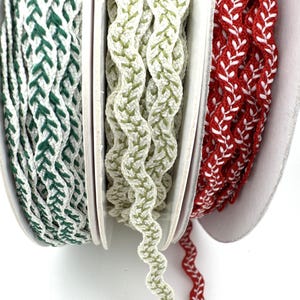 May include: Three spools of decorative braided trim in green and white, light green and white, and red and white. The trim has a textured, woven appearance, ideal for crafts and embellishments.