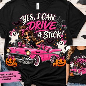 Può includere: Una t-shirt nera con la grafica di una persona dai capelli castani con un fiocco rosa alla guida di un'auto decappottabile vintage rosa. Il testo "YES, I CAN DRIVE A STICK!" è circondato da illustrazioni di fantasmi, zucche e pipistrelli.