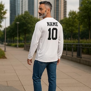 K&ouml;nnte beinhalten: Ein wei&szlig;es Langarmshirt mit dem Aufdruck "NAME 10" auf der R&uuml;ckseite in Schwarz.