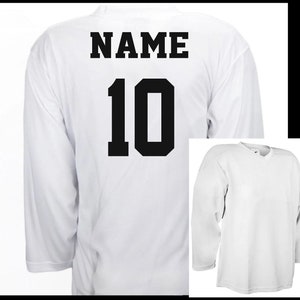 K&ouml;nnte beinhalten: Ein wei&szlig;es Hockeytrikot mit schwarzer Beschriftung auf der R&uuml;ckseite. Das Trikot hat den Schriftzug "NAME" und die Nummer "10" auf der R&uuml;ckseite.