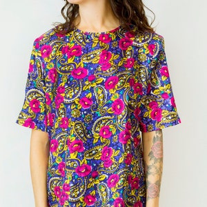 K&ouml;nnte beinhalten: Ein kurz&auml;rmeliges, blaues, pinkfarbenes und gelbes Hemd mit floralem Druck und Paisley-Muster.