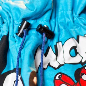 May include: Close-up of a blue drawstring bag featuring a cartoon character design. The bag has black cord locks and blue drawstrings. The word "MICKEY" is printed in white on the bag.