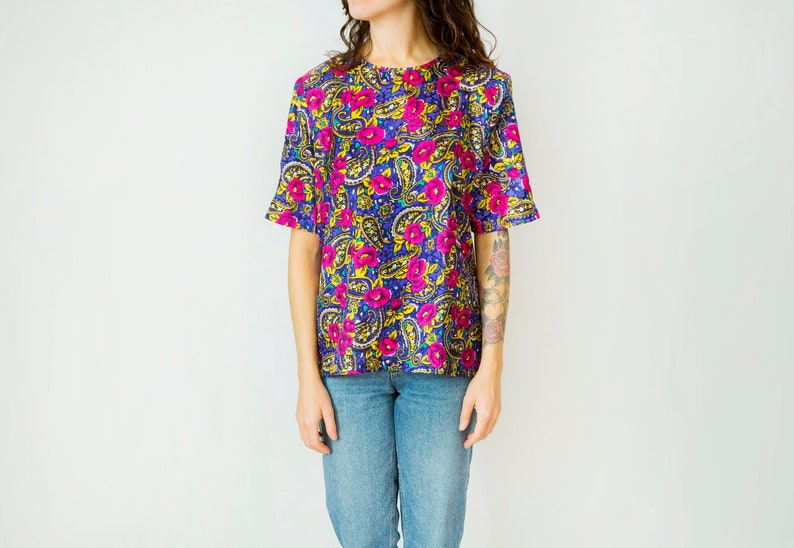 K&ouml;nnte beinhalten: Ein kurz&auml;rmeliges, blaues, pinkfarbenes und gelbes Hemd mit floralem Druck und Paisley-Muster.
