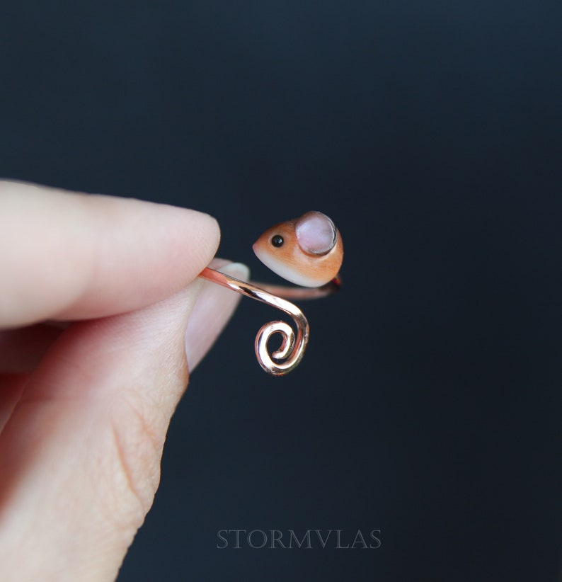 K&ouml;nnte beinhalten: Ein zarter Ring aus Kupferdraht mit einem kleinen, braunen und rosafarbenen Maus-Anh&auml;nger. Die Maus hat ein rosa Ohr und ein schwarzes Auge.