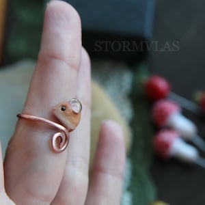 K&ouml;nnte beinhalten: Ein Ring aus Kupferdraht mit einer kleinen, braunen und wei&szlig;en Mausfigur. Die Maus hat eine Glasperle als Auge.