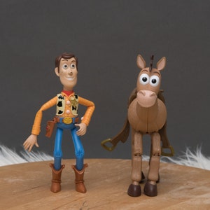 May include: Toy figures of Woody and Bullseye from the Toy Story franchise. Woody is wearing his signature cowboy hat, vest, and jeans. Bullseye is a brown horse with a saddle and bridle.