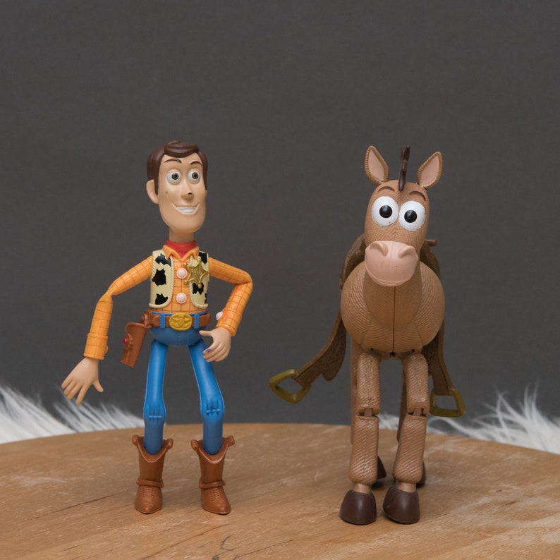 May include: Toy figures of Woody and Bullseye from the Toy Story franchise. Woody is wearing his signature cowboy hat, vest, and jeans. Bullseye is a brown horse with a saddle and bridle.