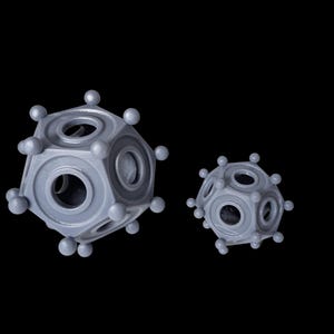 May include: Two gray, geometric, 3D-printed objects with spherical accents and circular openings. The larger object is in the foreground, with the smaller one behind it, both against a black background.