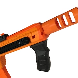 May include: Orange and black toy gun with a black grip and a black rail system. The gun has a orange muzzle break with three holes.