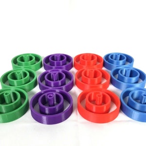 May include: Twelve colorful plastic rings, stacked in four groups of three. The rings are green, purple, red, and blue.