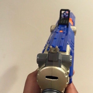 May include: A blue and silver toy gun with a red and black sight. The gun has a black barrel and a silver handle.