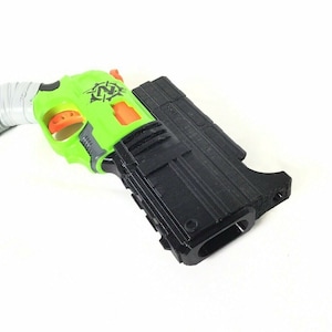 May include: A black and green toy gun with an orange trigger and a white grip. The gun has a black magazine and a "Z" logo on the side.